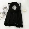 Detail of black cashmere-like scarf featuring soft pompom tassels and cozy knitted texture - Black