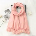 Detailed shot of pink cashmere-like scarf with soft pom-pom fringe on a white fur rug - Pink