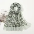 Detail of grey-green scarf featuring geometric patterns and delicate fringe edges - Light Green