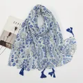 Close-up of white linen floral scarf with blue tassels and decorative magazine props - White Base Blue Floral Style (XB962)