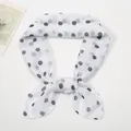 Detail of a thin chiffon square scarf with black polka dots tied in an elegant bow knot - White