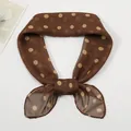 Close-up of brown chiffon scarf with yellow polka dots tied in a stylish bow knot - Coffee