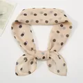 Close-up of lightweight apricot polka dot chiffon scarf with soft vintage tie knot detail - Beige
