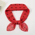 Detail of red chiffon scarf with black polka dots tied in a decorative bow style - Red
