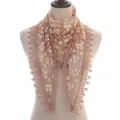 Detailed close-up of light brown floral lace triangle scarf with delicate tassel edges - Camel
