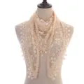 Detail showing sheer lace floral patterns and scalloped fringe on a beige triangle scarf - Beige