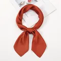 Detail of silk satin neck scarf tied in a bow showing smooth brick red texture - One Size / Caramel