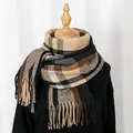 Close-up of thick winter plaid scarf with fringe tassels on mannequin in soft lighting - Black Camel