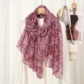 Detail shot of sheer red marble print scarf paired with white shirt on elegant backdrop - Pink