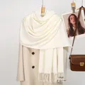 Detail of cream waffle knit scarf with tassels over a warm wool coat - 188x70cm / White