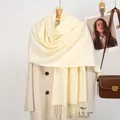 Detailed texture of beige cashmere-feel scarf with tassels paired with a wool coat - 188x70cm / Beige
