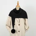 Detail view of a thick black knit scarf featuring a soft pom-pom on an elegant beige coat - 86*36cm / Black