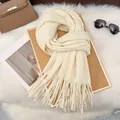 Detail of soft cream white milk velvet knit scarf with long tassels on a stylish background - White