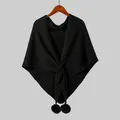 Detail of black knit shawl with a cross-knot design and faux fur pom-pom trim on wood hanger - 190 x 73 / Black