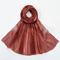 Close-up of lightweight metallic red-brown scarf fabric with smooth satin texture - Red