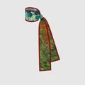 Detailansicht eines Twilly-Seidenschals mit grünem Blumenmuster und rotem Kontrastrand - Mohnfeld