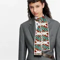 Detail of a red and green geometric pattern skinny silk scarf styled with a grey blazer - 120x8CM / Red Green Abstract Vortex (Color 4)
