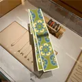 Detailed view of long silk headband scarf with green floral pattern over a jewelry stand - Picture Style 24