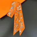 Detailed macro view of orange silk twilly featuring vintage key and tassel motifs for bags - Orange