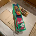 Artistic rectangular silk scarf with green edges and abstract guitar patterns on a display - Picture Style 4