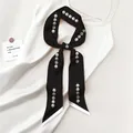 Detail of a black satin twilly scarf with pearl print tied on a white silk dress - Black Pearl String