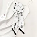 Close-up of narrow white silk scarf with minimalist black beaded print on a dress - White Pearl String