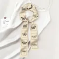 Beige zijdeachtige lint sjaal met zwarte vlinderprint op een witte jurk gebonden - Beige Vlinder Libel (Pauwblauw SKU)