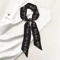 Elegante zwarte smalle zijden sjaal met witte rozenprint op een witte zijden jurk geknoopt - Zwart Wit Roos (Roze SKU)