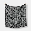 Classic black and white paisley silk scarf displayed on a textured white background - Black