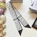 Detail of black and white Twilly scarf with NEVER MIND print and sharp diagonal cut - Letter Print