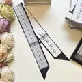 Detail of double-sided silk twilly scarf with geometric patterns and artistic script - Four Petal Flower