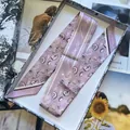Eleganter lavendelfarbener Seidenschal mit Muschelmuster in einer Blumenbox - Lila-Rosa