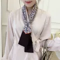 Close-up of double-layer satin scarf featuring classic paisley print and orange wavy trim - Black