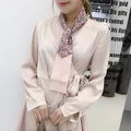 Close-up of champagne satin wrap dress featuring a detailed paisley print silk scarf - Pink