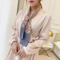 Elegant woman wearing a pink paisley print silk scarf with a satin v-neck wrap dress - Gray