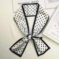 Detailed shot of white satin scarf with black polka dots tied next to fashion book - 80-100cm / White (Black Border)