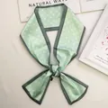 Detalle de pañuelo de seda verde menta con lunares atado en lazo con fondo de revista - verde claro