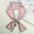 Detailed view of pink polka dot silk scarf tied in a bow on minimalist background - Pink