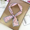 Detail of pink satin twilly scarf with heart patterns on a stylish wooden display - Pink
