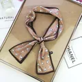 Detail showing elegant silk-feel skinny scarf with white heart pattern and tied knot - Coffee