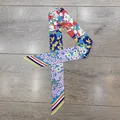 Dettaglio di un foulard in seta a fiori multicolore con punte a righe su legno naturale - 80-100cm x 5cm / Blu