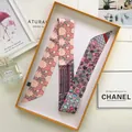 Sciarpa twilly in seta rosa con motivi floreali e accenti blu in una scatola arancione - Rosa