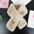 Close-up of soft khaki faux fur scarf with a premium leather brand tag on black surface - Apricot Camel