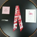 Dettaglio flat lay di un foulard in seta rossa con cuori su un piatto decorativo nero - Rosso