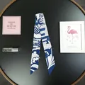 Dettaglio di un foulard Twilly in seta blu e bianca con motivi geometrici su vassoio - Blu