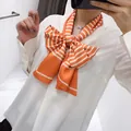 Elegant narrow long silk scarf with orange and white stripes tied as a decorative bow - Orange Red