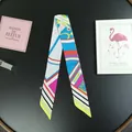 Close-up of long silk-feel scarf with vibrant geometric patterns and Paris text detail - Goose Yellow
