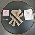 Detail of beige faux fur scarf with black gold tweed patchwork and crossover design - Camel