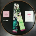 Detail of Van Gogh floral silk scarf with brand tag on decorative black tray - Van Gogh Series / White Rose Pendant