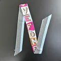 Close-up of a long silk twilly scarf with colorful monogram pattern for bag handles - Long Ribbon / Light Blue